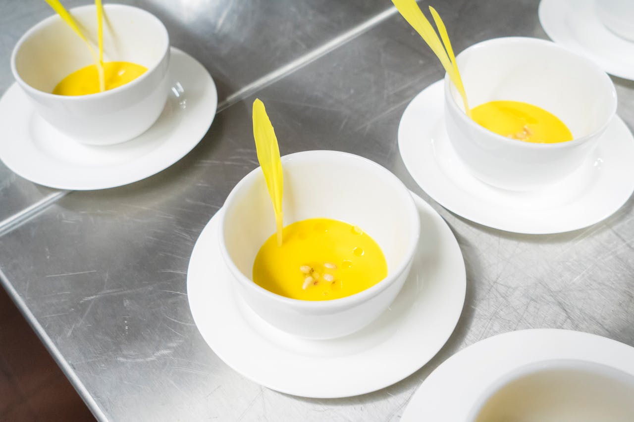 A high-angle view of creamy yellow soup garnished in elegant white bowls, exuding a modern culinary presentation.